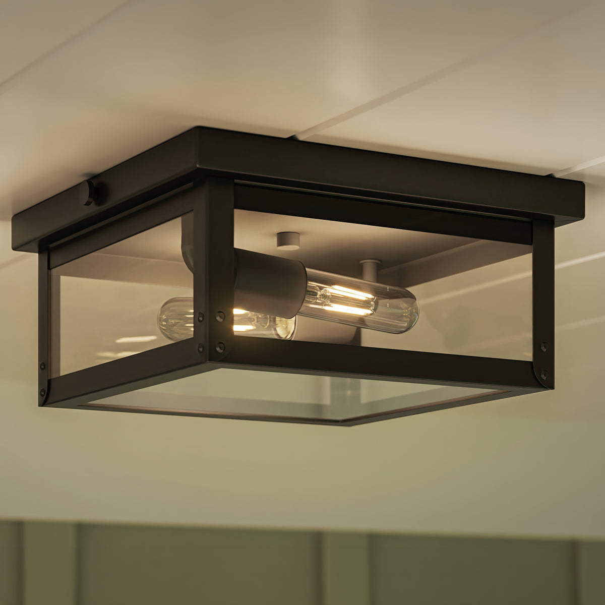 Black outdoor ceiling light fixture with clear glass cover on a white wall. 