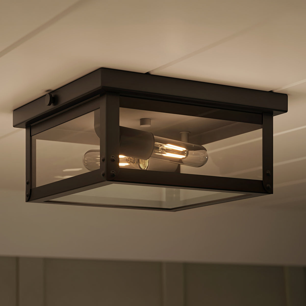 Ceiling-mounted light fixture with black frame and glass cover on a neutral ceiling. 